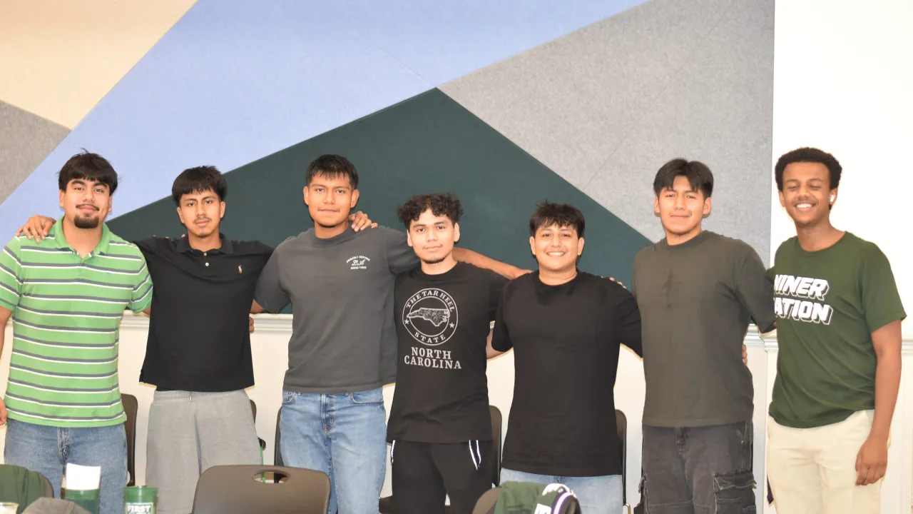 7 First-Gen students smiling in Lucas Room during the Gold Rush First-Gen Meet & Greet.