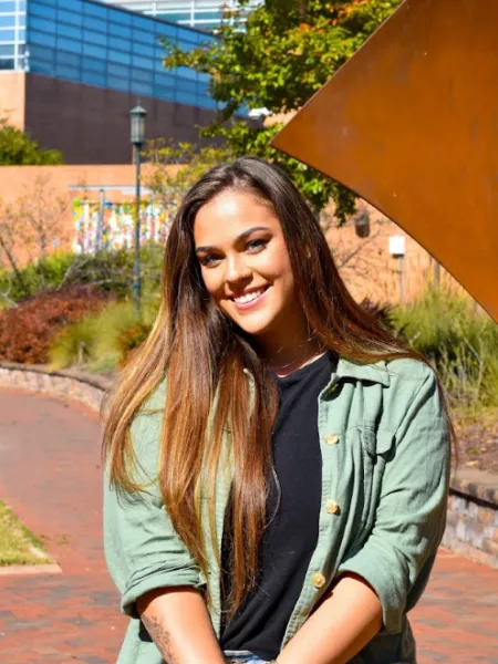 person wearing a green top with brown hair smiling 