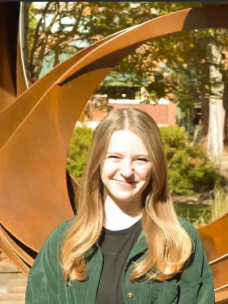 person wearing a green top smiling with blondish brown hair