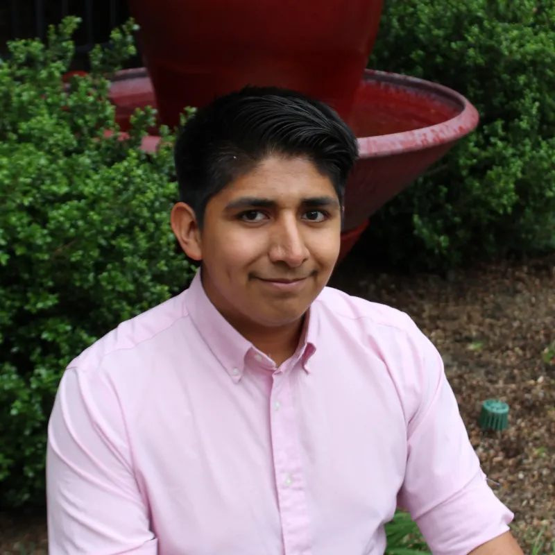 Image of scholarship recipient sitting outside in front of a burgundy planter.