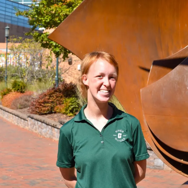 person with red hair smiling wearing a green t-shirt 