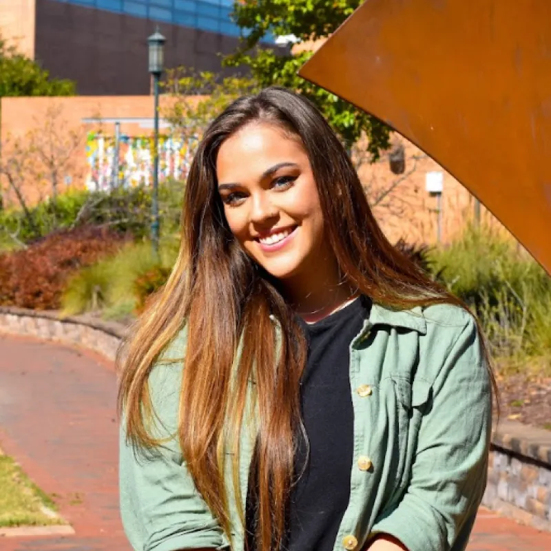 person wearing a green top with brown hair smiling 